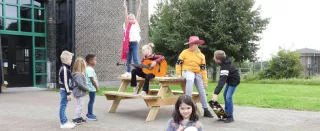 Groep kinderen op het schoolplein bij een picknicktafel